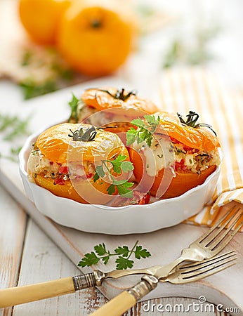 Stuffed tomatoes, baked yellow tomatoes stuffed with bulgur, vegetables and cheese with the addition of aromatic herbs in a baking Stock Photo