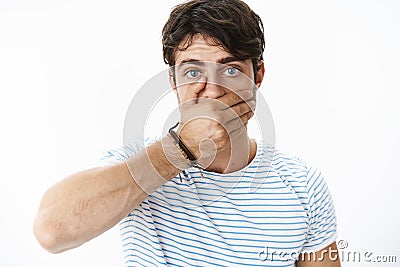 Stunned and concerned handsome guy feeling intense and worried covering mouth with palm as realising saying stupid Stock Photo