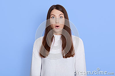 Stunned winsome woman with dark hair, keeps mouth widely opened, afraids of something astonishing, dressed in white casual shirt, Stock Photo
