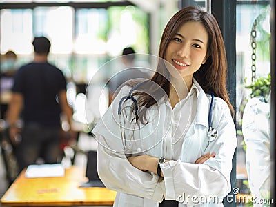 Asian young practitioner in a white gown and stethoscope crossed her arms Stock Photo