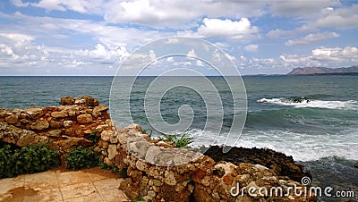Stunning bright panoramic views of the Cretan sea from the city of Chania, with part of the ruined old walls in the foreground. Stock Photo
