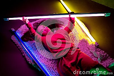 Caucasian female inclusive model posing on studio background in neon light Stock Photo