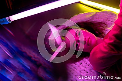 Caucasian female inclusive model posing on studio background in neon light Stock Photo