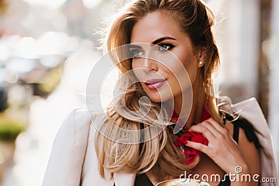 Stunning european girl with glamorous make-up looking away touching her red scarf. Close-up portrait of beautiful fair Stock Photo