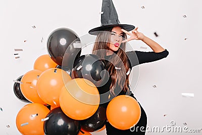 Stunning european woman in carnival costume enjoying photoshoot. Indoor portrait of glad girl holding helium balloons in Stock Photo