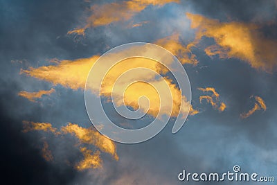 Stunning fluffy clouds illuminated by disappearing rays at sunset floating across sunny blue sky to change weather Stock Photo