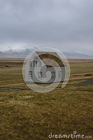 Stunning Iceland landscape photography. Lonely house in the fields with snowy mountains in the background Stock Photo