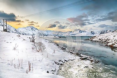 Stunning morning view of Torsfjorden fjord with cracked ice and snowy mountain peaks at background Stock Photo