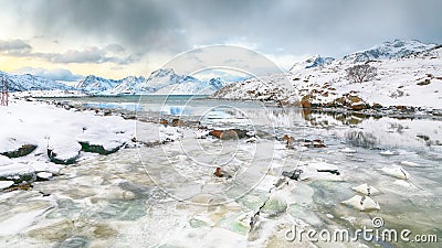 Stunning morning view of Torsfjorden fjord with cracked ice and snowy mountain peaks at background Stock Photo