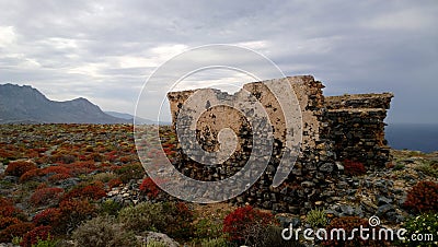 Stunning mystical view of the destroyed remains of walls on the island Gramvousa. Bright red bushes on the rocky rocky ter Stock Photo