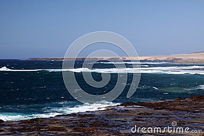 Stunning natural viewpoint with bare dry hills, turquoise lagoon and furious wild sea at north-west coast of Fuerteventura, Canary Stock Photo