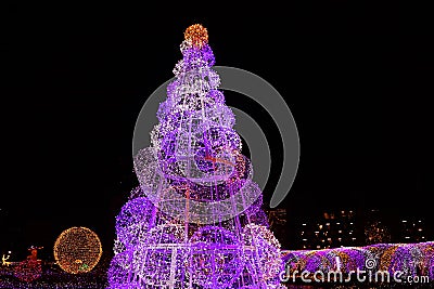 Stunning Purple and Gold Giant Christmas Tree Glittering Against Night Sky Stock Photo