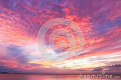 Stunning red and purple and yellow sunset reflecting on the ocean Stock Photo