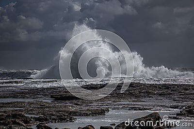 the waves are crashing into the ocean on the rocks in the water Stock Photo