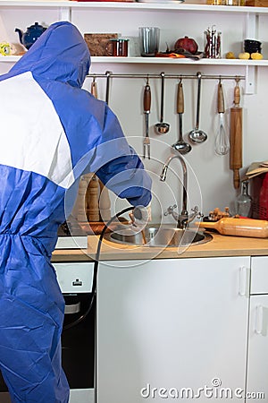 Stunning shot of a professional pest exterminator spraying a chemical on a kitchen sink Stock Photo