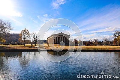 A stunning shot of the still blue lake water surrounded by gorgeous autumn trees in the park with a view of The Parthenon Stock Photo