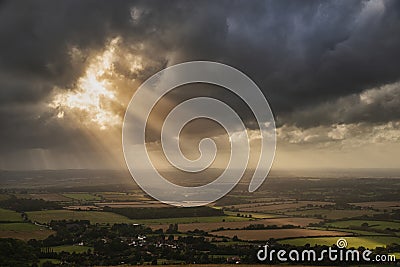 Stunning Summer landscape image of escarpment with dramatic storm clouds and sun beams streaming down Stock Photo