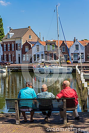 Stunning views over historic dutch yacht harbour watched by senior males sitting on bench Editorial Stock Photo