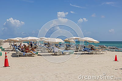 Stunning vista of white sandy beach along Atlantic Ocean with people relaxing on sun loungers beneath umbrellas. Editorial Stock Photo