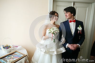Stunning wedding couple stands in the room looking at each other Stock Photo