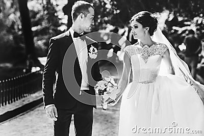 Stunning wedding couple walks along the pass in park Stock Photo