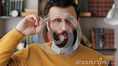 Stupid. Irritated bearded man in glasses in office or apartment room looks at camera and twirls his finger at his temple Stock Photo