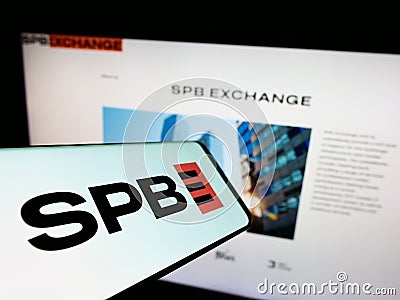 Mobile phone with logo of Russian financial marketplace SPB Exchange on screen in front of business website. Editorial Stock Photo