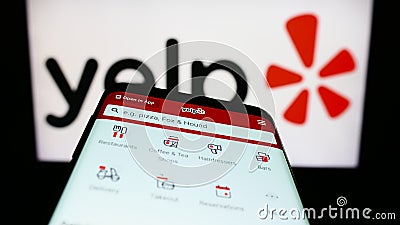 Mobile phone with webpage of US review platform company Yelp Inc. on screen in front of business logo. Editorial Stock Photo