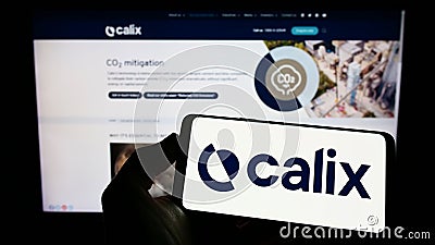 Person holding cellphone with logo of Australian technology company Calix Limited on screen in front of business webpage. Editorial Stock Photo