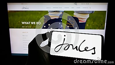 Person holding cellphone with logo of British retail company Joules Group plc on screen in front of business webpage. Editorial Stock Photo