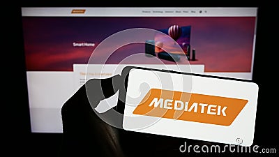 Person holding cellphone with logo of Taiwanese semiconductor company MediaTek Inc. on screen in front of webpage. Editorial Stock Photo