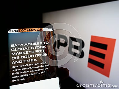 Person holding cellphone with webpage of Russian financial marketplace SPB Exchange on screen in front of logo. Editorial Stock Photo