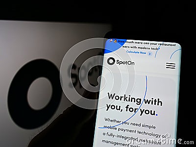 Person holding cellphone with website of US software company SpotOn Transact LLC on screen in front of logo. Editorial Stock Photo