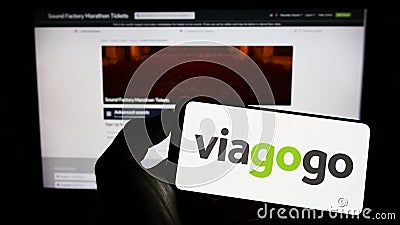 Person holding mobile phone with logo of American ticket exchange platform company Viagogo on screen in front of web page. Editorial Stock Photo