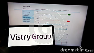 Person holding mobile phone with logo of British housebuilding company Vistry Group plc on screen in front of web page. Editorial Stock Photo