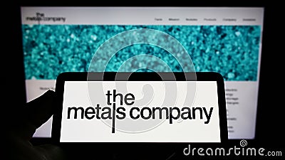 Person holding smartphone with logo of mining company TMC The Metals Company Inc. on screen in front of website. Editorial Stock Photo
