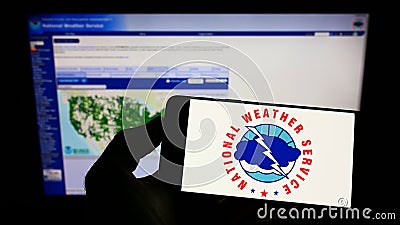 Person holding smartphone with logo of US agency National Weather Service (NWS) on screen in front of website. Editorial Stock Photo