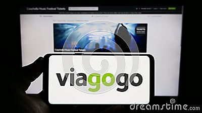 Person holding smartphone with logo of US ticket exchange platform company Viagogo on screen in front of website. Editorial Stock Photo