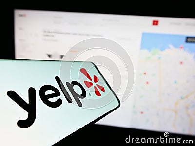 Smartphone with logo of American review platform company Yelp Inc. on screen in front of business website. Editorial Stock Photo