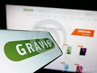 Smartphone with logo of Gravis Computervertriebsgesellschaft mbH on screen in front of business website. Editorial Stock Photo