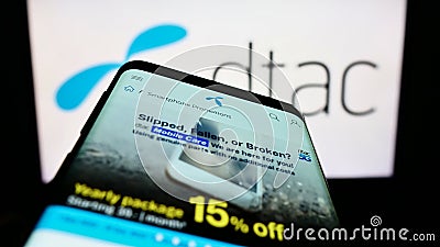 Smartphone with webpage of Total Access Communication Public Company Limited (DTAC) on screen in front of logo. Editorial Stock Photo