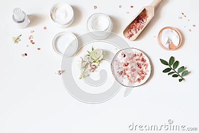Styled beauty frame, web banner. Skin cream, tonicum bottle, dry flowers, leaves, rose and Himalayan salt. White table Stock Photo
