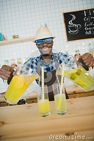 stylish african american bartender pouring lemonades into glasses on bar counter Stock Photo