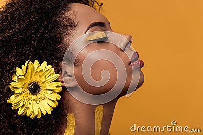 Stylish african american woman with artistic make-up and gerbera in hair dreaming Stock Photo