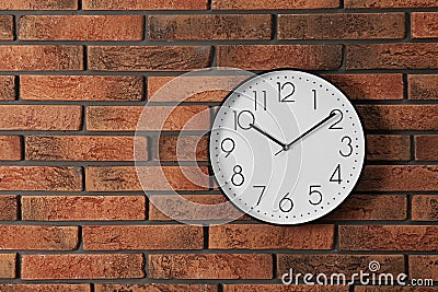 Stylish analog clock hanging on brick wall Stock Photo