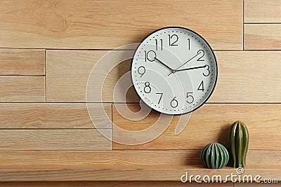 Stylish analog clock hanging on wooden wall. Stock Photo