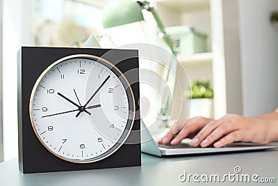 Stylish analog clock on table in office Stock Photo