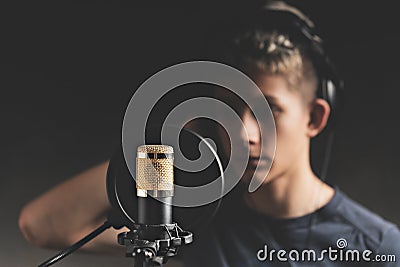 Stylish attractive guy with dreadlocks is recording a song in the studio. A young singer in black studio headphones stands in Stock Photo