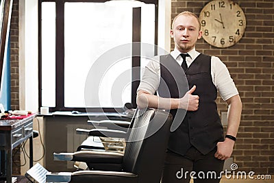 Barber invites to have seat on chair at barbershop Stock Photo