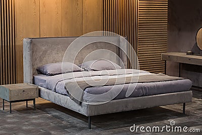 Stylish bedroom in a loft style, with wooden partitions with slats, with soft light, stylish bedroom design. Double bed with gray Stock Photo